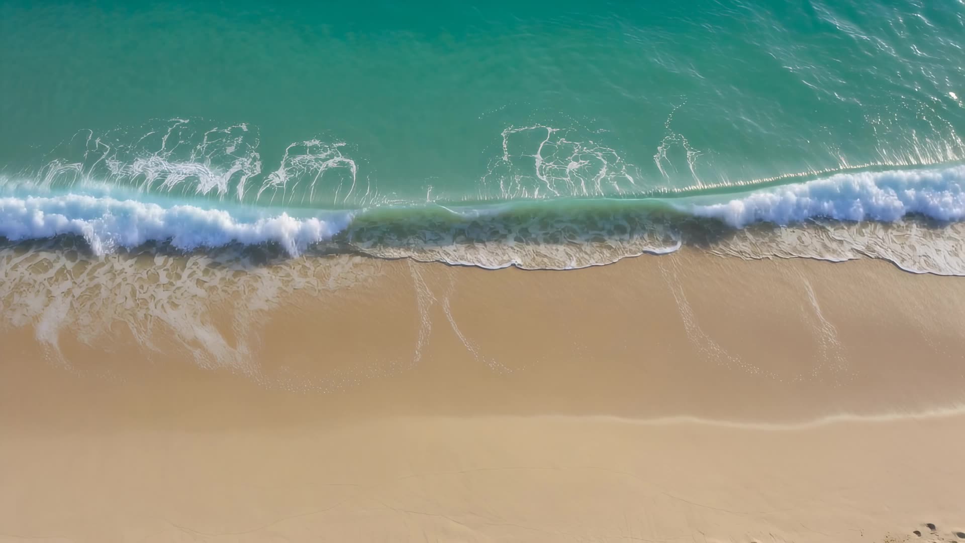 Top-down aerial of waves breaking on sand