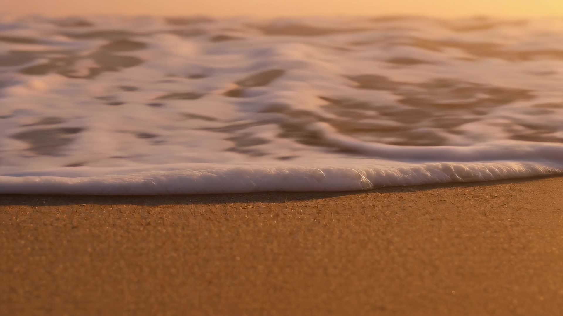 Wave foam washing over sand, tight close-up, sunset version