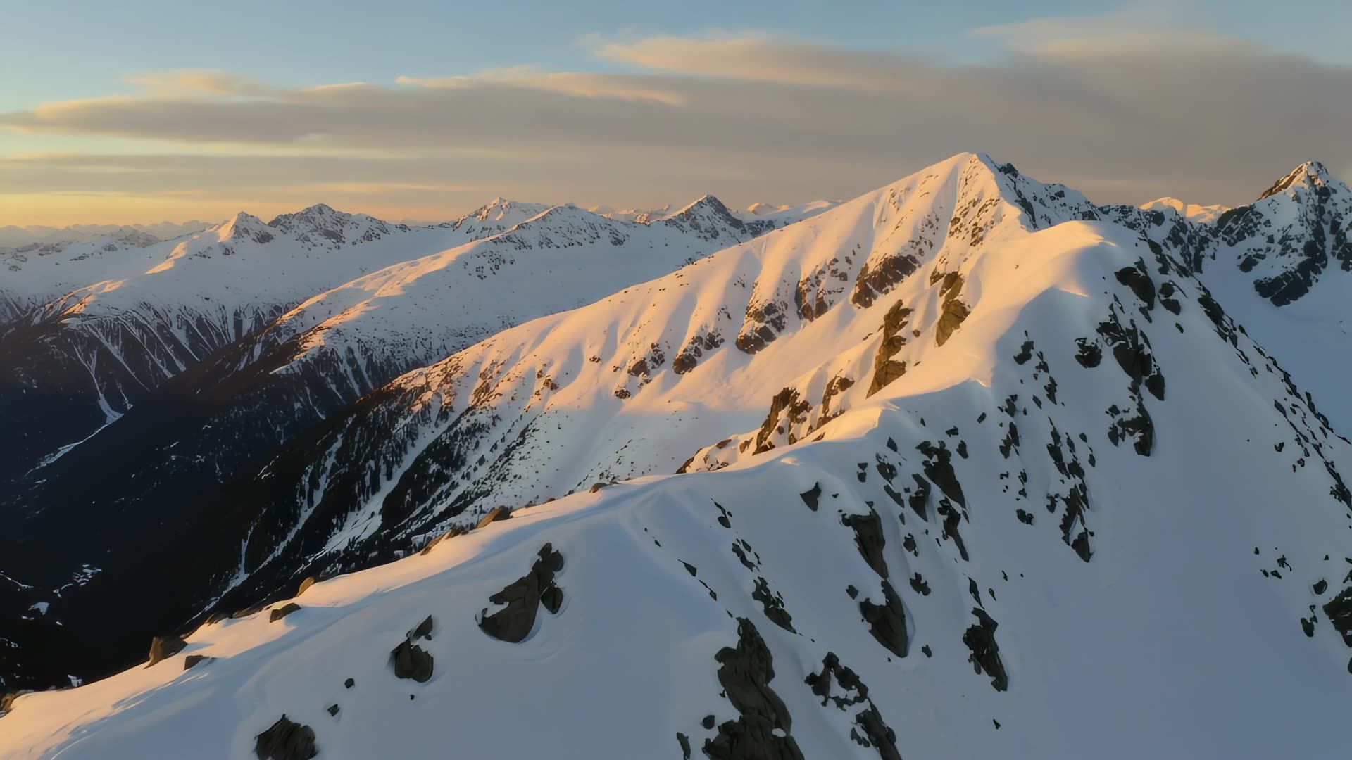Aerial over snow-capped ridge, golden hour