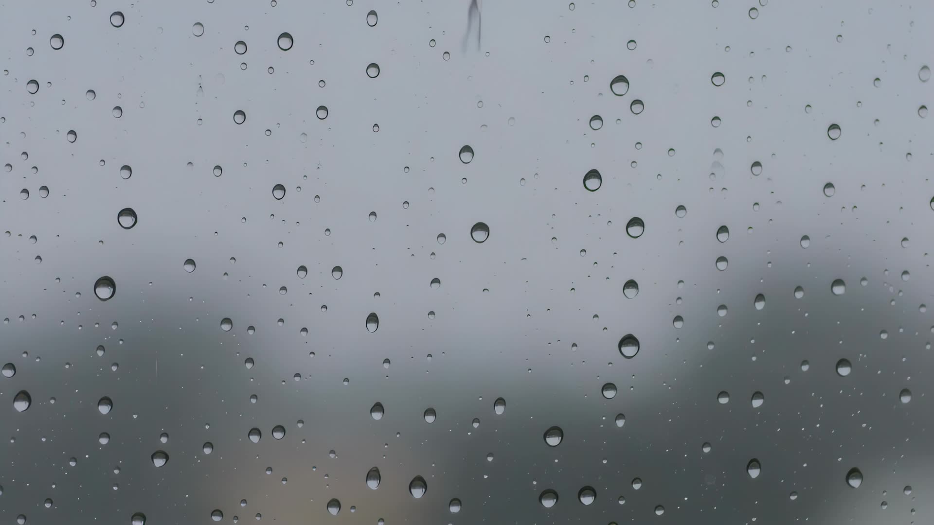 Raindrops running down a window, close-up